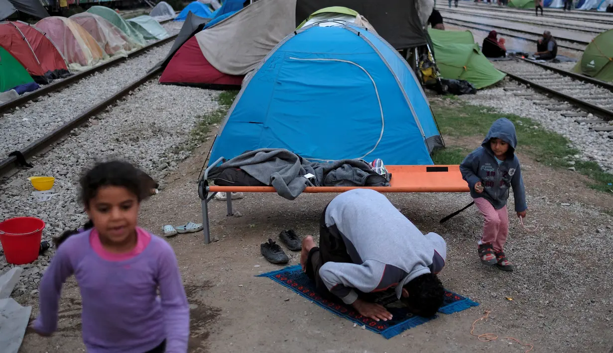 Seorang imigran melakukan ibadah di sebuah stasiun kereta api di sebuah kamp darurat bagi para migran dan pengungsi di perbatasan Yunani-Macedonia dekat desa Idomeni, Yunani, 10 Mei 2016. (REUTERS / Marko Djurica)