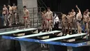 Staf dengan masker memeriksa para atlet dalam urutan yang benar saat melakukan pemanasan sebelum penyisihan Loncat Indah 3 Meter Putra Sikronisasi di Kejuaraan Dunia Loncat Indah FINA 2021 dan uji coba Olimpiade Tokyo 2020, di Tokyo Aquatics Center, Minggu (2/5/2021). (AP Photo/Eugene Hoshiko)