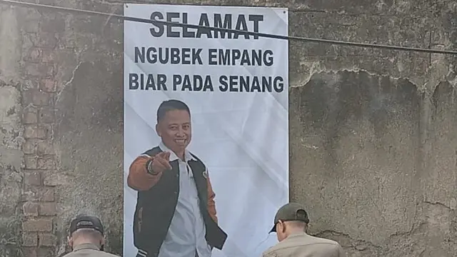 Anggota Satpol PP Kota Depok saat menurunkan spanduk Sekda Kota Depok, Supian Suri saat kegiatan ngubek Empang di Cilodong, Depok.