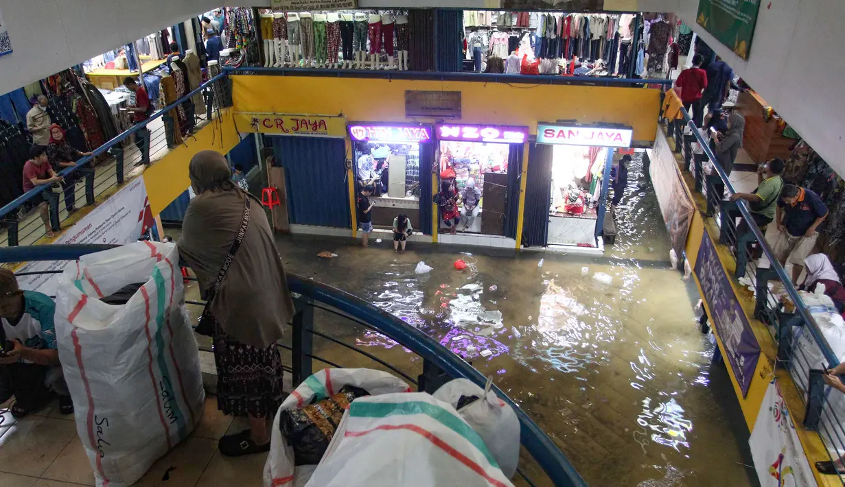Kondisi ini diduga berkaitan dengan saluran drainase di luar area pasar yang tidak berfungsi optimal, sehingga air meluap dan masuk ke dalam kawasan perdagangan. Tampak dalam foto, aktivitas pedagang dan pembeli di Pasar Cipulir, Jakarta, Jumat (23/1/2026). (merdeka.com/Arie Basuki)