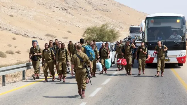 Tentara Israel yang membawa barang-barang berjalan di jalan dekat lokasi serangan di sebelah timur Desa Tubas, di utara Tepi Barat yang diduduki [Ahmad Gharabali/AFP]