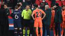 Wasit Ovidiu Hategan berbicara dengan ofisial tim istanbul Basaksehir usai dihentikannya laga lanjutan Liga Champions Grup H melawan Paris Saint-Germain di Parc des Princes Stadium, Selasa (8/12/2020). (AFP/Franck Fife)