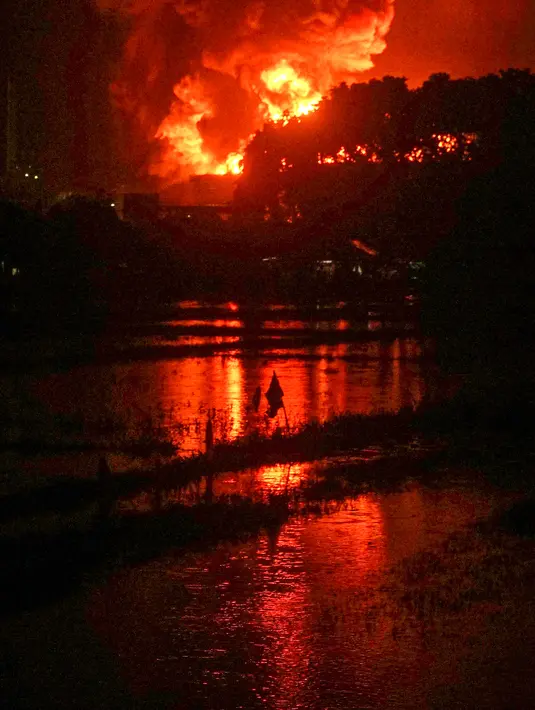 Asap dan api terlihat dari kejauhan setelah sebuah tangki minyak milik Pertamina, sebuah perusahaan minyak dan gas bumi milik negara, terbakar tanpa sebab yang jelas di Cilacap, Jawa Tengah (13/11/2021). (AFP/Dida Nuswantara)