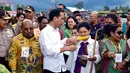 Presiden Joko Widodo tampak menyuapi jagung bakar ke Ibu Negara, Iriana saat mengikuti ‎upacara Bakar Batu bersama masyarakat Pegunungan Tengah Papua di Stadion Mini Pendidikan, Distrik Wamena, Kabupaten Jayawijaya‎, Rabu (30/12). (Rumgapres)