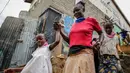 Margaret Andeya membawa anak (kanan) dan putri tetangganya pulang setelah rambutnya ditata dengan model corona Covid-19 di daerah kumuh Kibera, di Kenya, 3 Mei 2020. Corona telah menghidupkan kembali gaya rambut di Afrika Timur yang memiliki lonjakan kepang bentuk khas virus (AP/Brian Inganga, File)