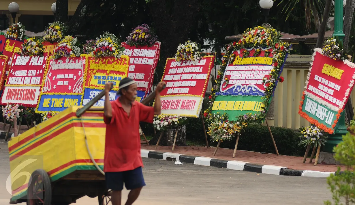Warga melintasi deretan karangan bunga yang diletakkan di depan Mabes Polri, Jakarta, Rabu (3/5). Ratusan karangan bunga itu terus berdatangan dan mengelilingi gedung Mabes Polri di Jalan Trunojoyo Jakarta Selatan. (Liputan6.com/Helmi Fithriansyah)