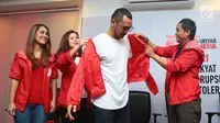 Giring Nidji dipakaikan jaket merah usai mendaftarkan diri menjadi anggota Partai Solidaritas Indonesia (PSI) di Jakarta, Rabu (6/9). Giring juga mendaftar sebagai calon legislatif dari PSI dalam Pemilu Legislatif 2019. (Liputan6.com/Herman Zakharia)