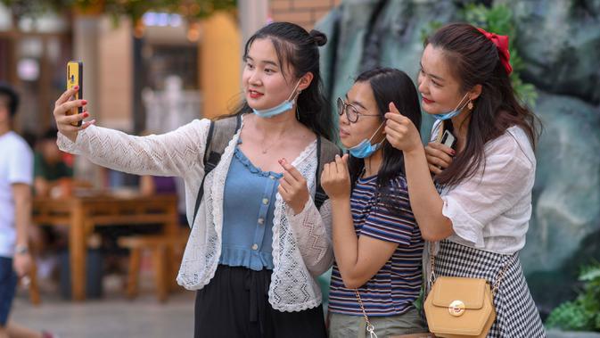 Para wisatawan berfoto saat mengunjungi Grand Bazaar Food Street di Urumqi, ibu kota Daerah Otonom Uighur Xinjiang, China barat laut, pada 4 Juli 2020. (Xinhua/Zhao Ge)