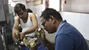 Pekerja India memeriksa batu berlian di bengkel pemotongan dan pemolesan berlian di Ahmedabad (23/7/2019). India merupakan pusat pemotongan dan pemolesan berlian terbesar di dunia. (AFP Photo/Sam Panthaky)