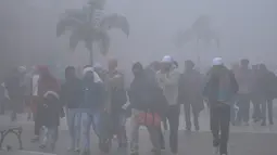 Orang-orang berjalan di sepanjang jalan Heritage di tengah kondisi berkabut pada Hari Tahun Baru, di Amritsar (1/1/2021). Sebagian besar India utara mencatat suhu yang menusuk tulang dan diselimuti kabut tebal sementara di Kashmir diselimuti salju pada Hari Tahun Baru. (AFP/Narinder Nanu)