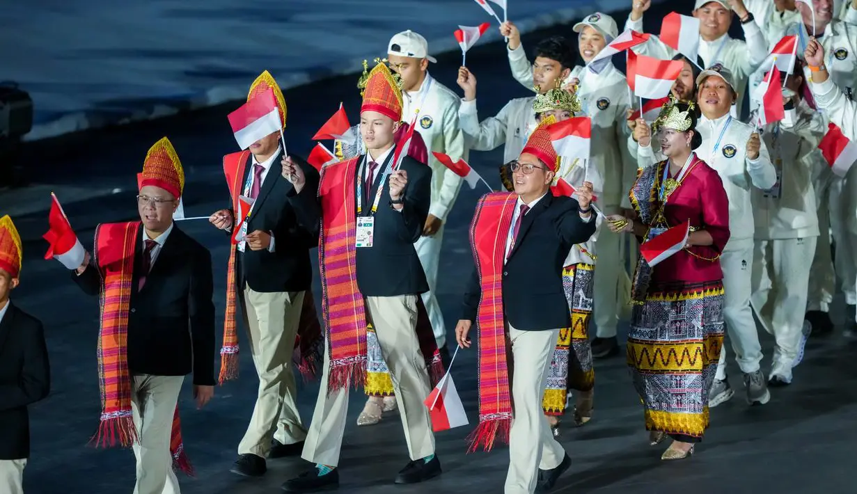 Kontingen Indonesia tampil mengunakan setelan formal hitam, Ulos, dan ikat kepala adat Sumatera Utara dan kebaya merah yang dipadukan dengan kain Tapis dan mahkota Siger Lampung di Opening Ceremony SEA Games Thailand 2025 yang digelar di Rajamanggala Stadium pada Selasa (9/12/2025) malam WIB. (Dok. NOC Indonesia)