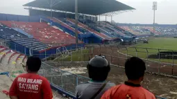 Orang-orang memeriksa kerusakan setelah tragedi kerusuhan pada pertandingan sepak bola antara Arema Vs Persebaya di Malang, Jawa Timur, Minggu (2/10/2022). Korban meninggal dunia dalam kejadian tersebut bertambah dua orang menjadi 129 orang. (AP Photo/Hendra Permana)