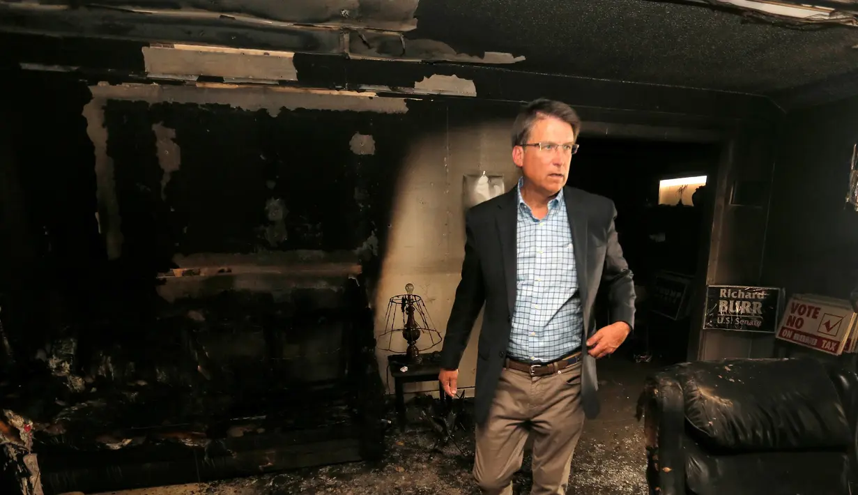 Gubernur North Carolina Pat McCrory meninjau kerusakan yang disebabkan serangan bom di Kantor Partai Republik, Orange County, Senin (17/10). Dinding bagian dalam gedung itu terlihat menghitam akibat kebakaran yang dipicu bom molotov. (REUTERS/Chris Keane)