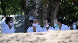 Umat Hindu mengenakan face shield menghadiri upacara Melasti menjelang Hari Raya Nyepi di Pantai Kuta, Bali (11/3/2021). Upacara Melasti dilakukan oleh perwakilan desa adat dengan jumlah terbatas serta menerapkan protokol kesehatan untuk mencegah penyebaran pandemi COVID-19. (AFP/Sonny Tumbelaka)