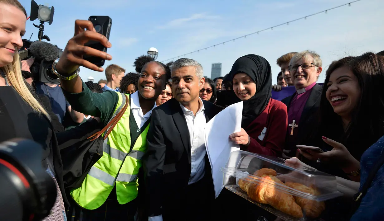 Walikota London terpilih Sadiq Khan berselfie dengan pendukung saat tiba untuk hari pertamanya bekerja di Balai Kota di London, Inggris (9/5). Pria 45 tahun ini merupakan Wali Kota Muslim Pertama di London dan kedua di Eropa. (REUTERS / Hannah McKay)