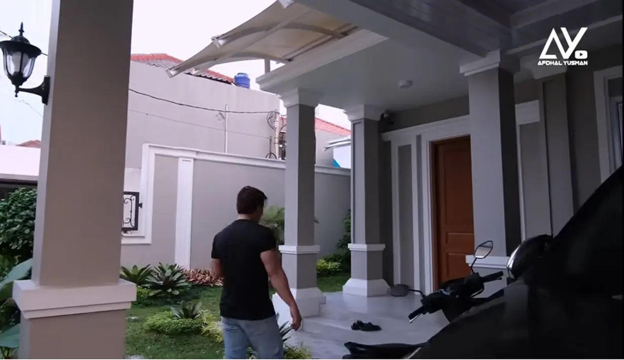 Potret halaman rumah baru Angga Wijaya. Suasana asri halaman depan dengan beberapa tanaman dan rumput. [Youtube/Afdhal Yusman]