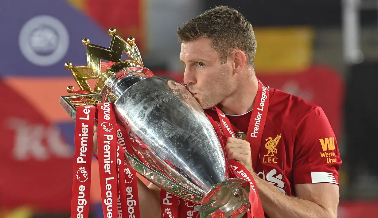 Gelandang Liverpool, James Milner berpose dengan mencium trofi juara Liga Inggris 2019/2020 dalam acara perayaan gelar usai laga menghadapi Chelsea di Anfield Stadium, Liverpool (22/7/2020). James Milner, satu-satunya pemain yang hingga kini masih aktif bermain, menghuni posisi ketiga daftar 10 pemain dengan penampilan terbanyak di Liga Inggris dengan 618 penampilan. Total membela 5 klub, ia tercatat tiga kali meraih trofi Liga Inggris, 2 kali bersama Manchester City (2011/2012 dan 2013/2014) dan sekali bareng Liverpool (2019/2020). (AFP/Paul Ellis)
