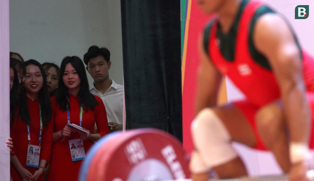 Mereka yang sebagian besar bertugas sebagai usher dalam prosesi penyeraham medali memanfaatkan momen menyaksikan para lifter berlomba dari sisi panggung. (Bola.com/Ikhwan Yanuar)