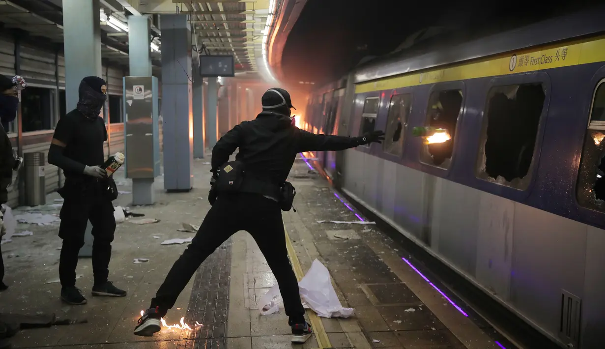 Seorang pelajar melempar bom molotov ke dalam kereta yang terparkir di Stasiun MTR Chinese University, Hong Kong, Rabu (13/11/2019). Gerakan antipemerintah Hong Kong yang telah berlangsung selama lima bulan bertindak semakin keras. (AP Photo/Kin Cheung)