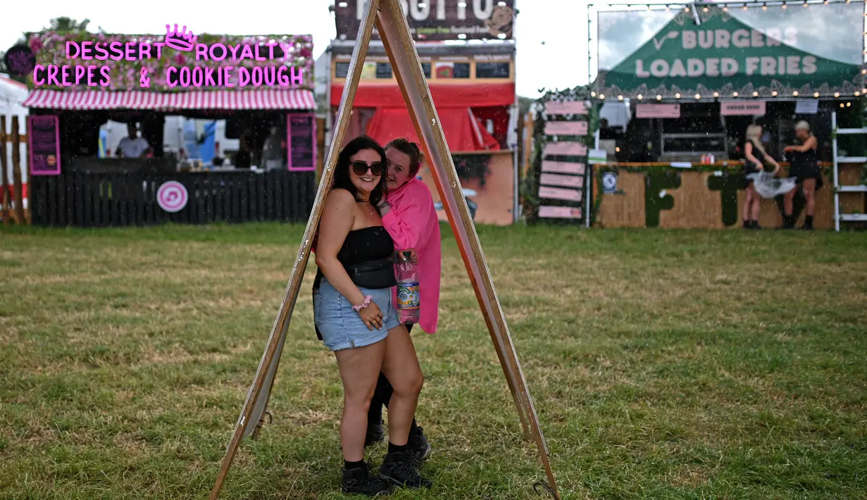 Pengunjung festival berlindung dari hujan pada hari pertama festival Glastonbury di desa Pilton, di Somerset, Inggris barat daya, pada 21 Juni 2023. (Photo by Oli SCARFF / AFP)
