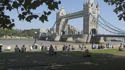 Seorang pria tidur di bawah naungan pohon di rumput dekat Potters Field menghadap Tower Bridge saat suhu mendekati 30 derajat celsius di London, Selasa (7/9/2021).  (AP Photo/Tony Hicks)