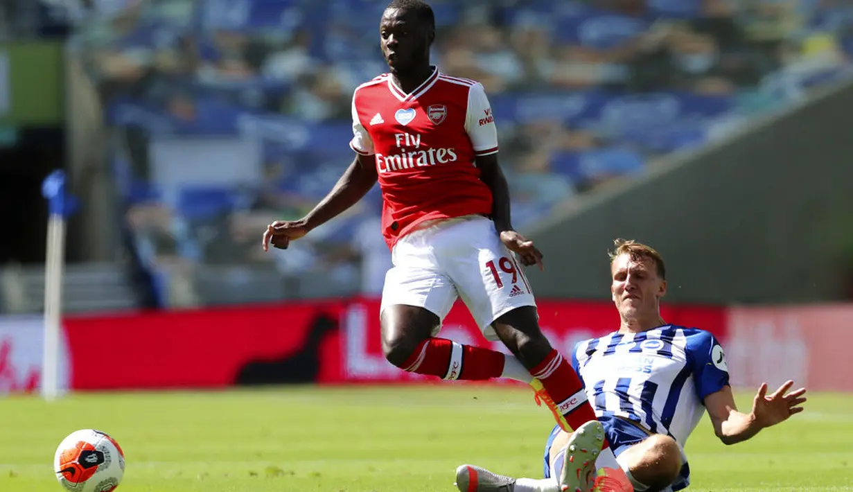 Pemain Brighton & Hove Albion, Dan Burn, berebut bola dengan pemain Arsenal, Nicolas Pepe, pada laga Premier League di Stadion Falmer, Sabtu (20/6/2020). Arsenal kalah 1-2. (AP/Gareth Fuller)