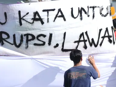 Warga menandatangani spanduk dukungan anti korupsi yang dibentangkan saat Hari Bebas Kendaraan di kawasan Bundaran HI, Jakarta, Minggu (10/12). Aksi dilakukan untuk memperingati Hari Anti-Korupsi Sedunia, 9 Desember. (Liputan6.com/Helmi Fithriansyah)