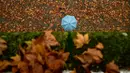 Pejalan kaki memakai payung menyusuri jalanan yang penuh dengan daun saat musim gugur di Pamplona, Spanyol, Selasa (20/11). (AP Photo/Alvaro Barrientos)