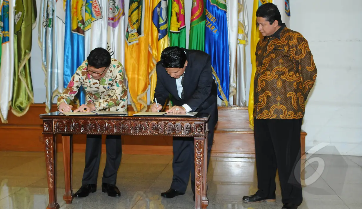Mendagri, Tjahjo Kumolo (kiri) bersama Ketua KPU Husni Kamil Manik  (tengah) menandatangani Data Agregat Kependudukan per-Kecamatan (DAK2) dari kemendagri ke KPU di Kantor Kemendagri, Jakarta, Jumat (17/4/2015). (Liputan6.com/Herman Zakharia)