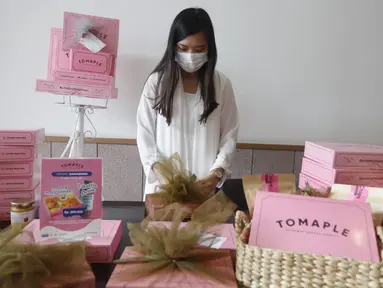 Pendiri Tomaple Gourmet Potato Donuts, Lala Ursula menyiapkan hampers untuk konsumen di salah satu outlet Tomaple di Jakarta, Sabtu (08/5/2021). Donat yang mampu berkreasi dengan pasar milenial dan didominasi warna pink mengusung tema #pinkboxhappines. (Liputan6.com/HO/Tomaple)