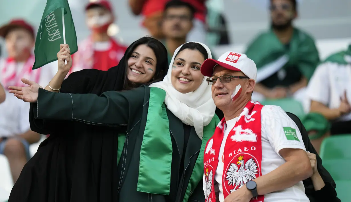 Dua fans wanita Arab Saudi berpose dengan pendukung Polandia sebelum pertandingan grup C Piala Dunia antara Polandia dan Arab Saudi, di Education City Stadium di Al Rayyan, Qatar, Sabtu, 26 November 2022. (AP Photo/Aijaz Rahi)