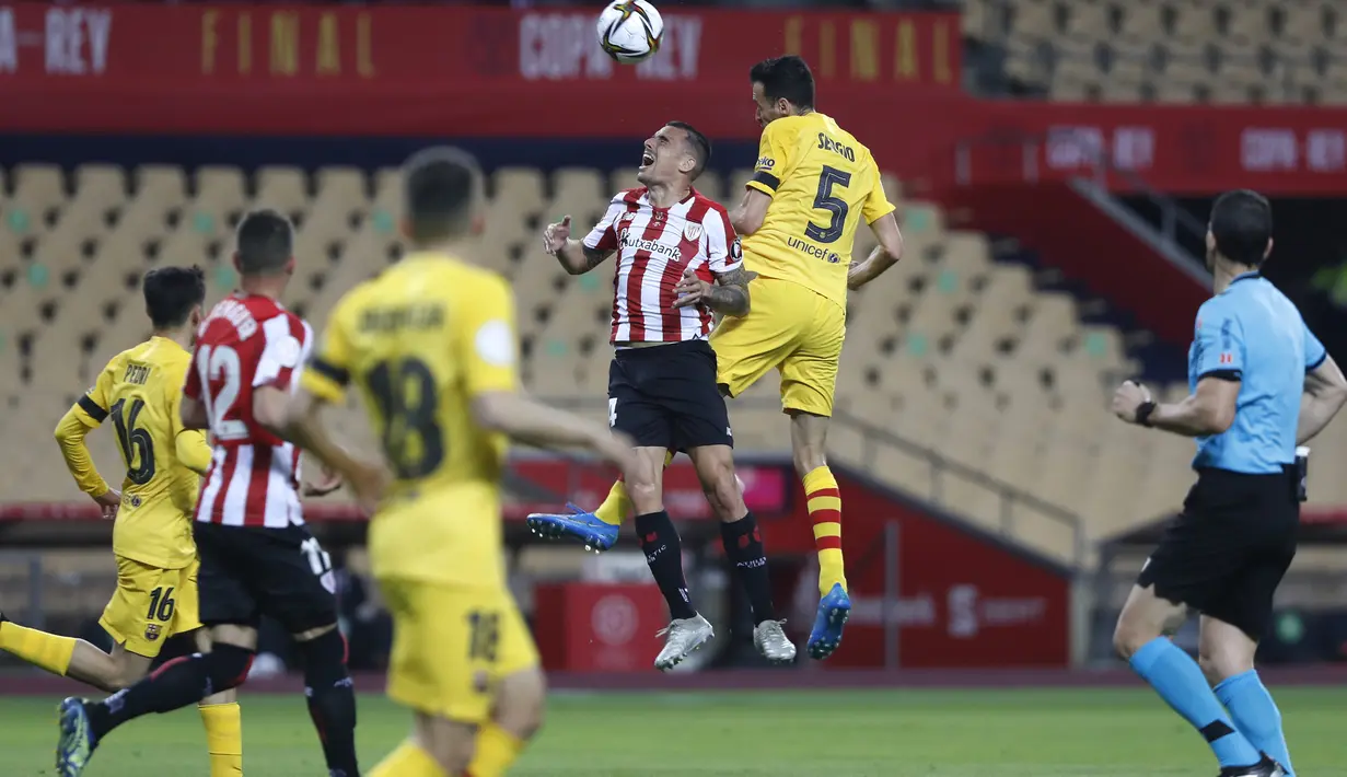 Gelandang Barcelona, Sergio Busquets berebut bola udara dengan pemain Athletic Bilbao, Inigo Martinez  pada final Copa del Rey Spanyol 2021 di stadion La Cartuja di Seville, Spanyol, Minggu (18/4/2021). Barcelona menang atas Athletic Bilbao 4-0. (AP Photo/Angel Fernandez)
