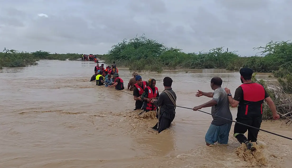 Petugas penyelamat membantu penduduk desa untuk mengevakuasi mereka dari daerah banjir yang disebabkan hujan lebat, di Lasbella, sebuah distrik di provinsi Baluchistan barat daya Pakistan (26/7/2022). Para pejabat mengatakan, pada hari Rabu, penyelamat yang didukung oleh pasukan menggunakan perahu dan helikopter untuk mengungsi ratusan orang terdampar dari barat daya Pakistan, di mana banjir yang dipicu oleh hujan telah menewaskan 104 orang sejak bulan lalu. (AP Photo/Hamdan Khan)