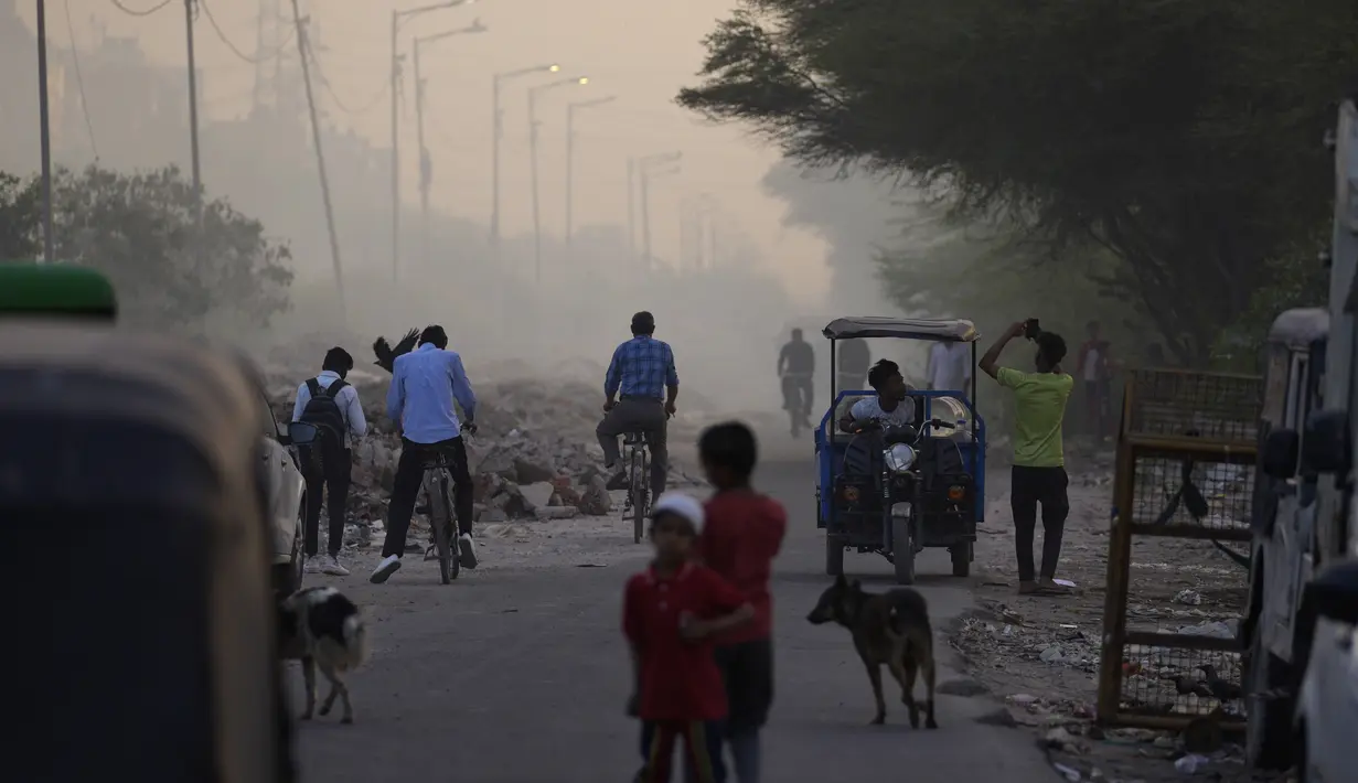 Orang-orang berjalan melintasi saat api besar melalap tempat pembuangan sampah Ghazipur di New Delhi, India (28/3/2022). Kebakaran besar terjadi di tempat pembuangan sampah di daerah Ghazipur Delhi timur yang menyebabkan kepulan asap besar menyelimuti wilayah tersebut. (AP Photo/Manish Swarup)