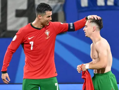 Penyerang Portugal #07 Cristiano Ronaldo mengucapkan selamat kepada #26 Francisco Conceicao setelah ia mencetak gol kedua timnya ke gawang Republik Ceko pada laga grup F Euro 2024 di Red Bull Arena, Leipzig, Rabu (19/6/2024) dini hari WIB. (Christophe SIMON / AFP)