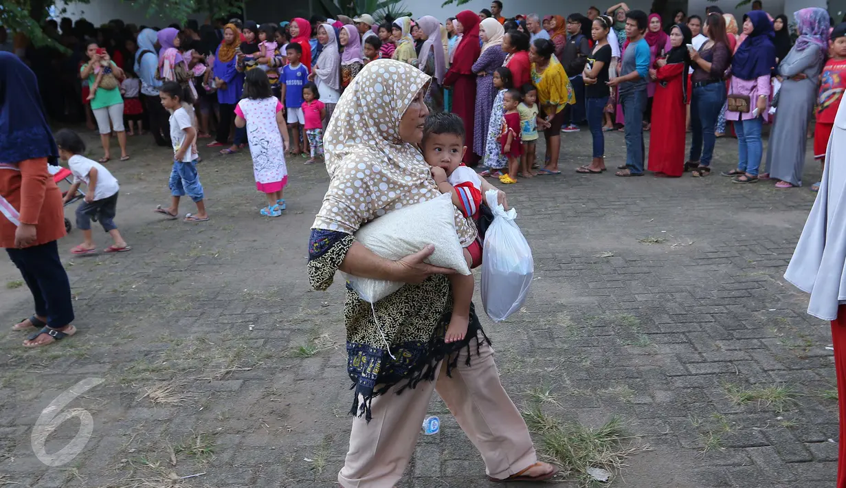 Seorang ibu membawa sembako usai mendapatkan paket sembako murah dari Indosiar di Joglo, Jakarta, Senin (13/6). Paket berisikan 5 kg beras, 2 liter minyak goreng, 1 kg gula pasir dan 1 kg tepung terigu dijual Rp 30 ribu‎. (Liputan6.com/Angga Yuniar)