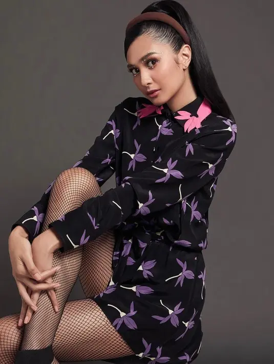Baju motif bunga warna ungu yang dipadukan dengan stocking jaring dan sepatu high heels hitam bikin penampilan Mikha terlihat segar tapi tetap kalem. (Instagram/dickyphotographie).