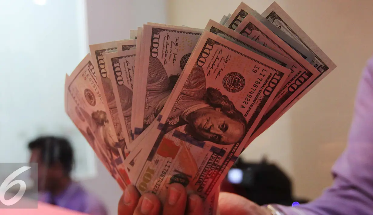 Petugas menunjukkan uang pecahan US$100 di penukaran uang, Jakarta, Rabu (23/9/2015). Mata uang Rupiah  sempat melemah ke level 14.655 per dolar AS pada perdagangan pukul 09.50 waktu Jakarta. (Liputan6.com/Angga Yuniar)