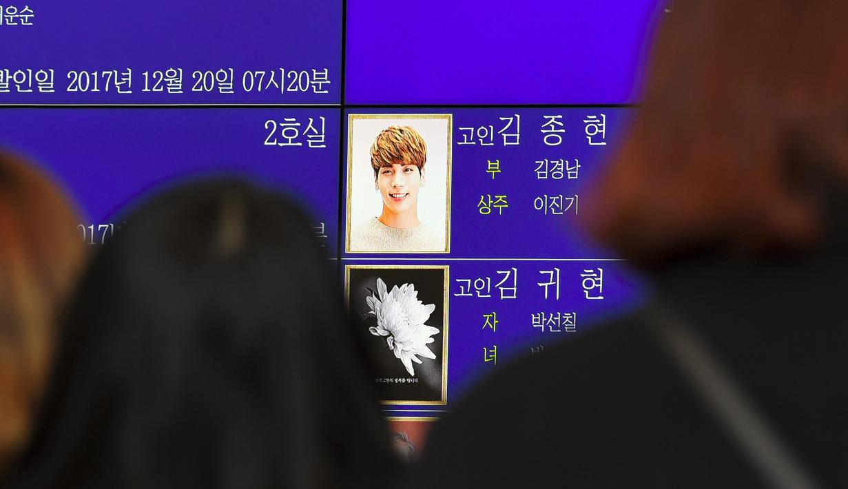 Para fans memandangi foto Jonghyun SHINee di papan elektronik di luar rumah duka Seoul Asan Hospital, Korea Selatan, Selasa (19/12). Jonghyun SHINee dikabarkan meninggal dunia karena bunuh diri menghirup karbon monoksida berlebih. (JUNG Yeon-Je / AFP)