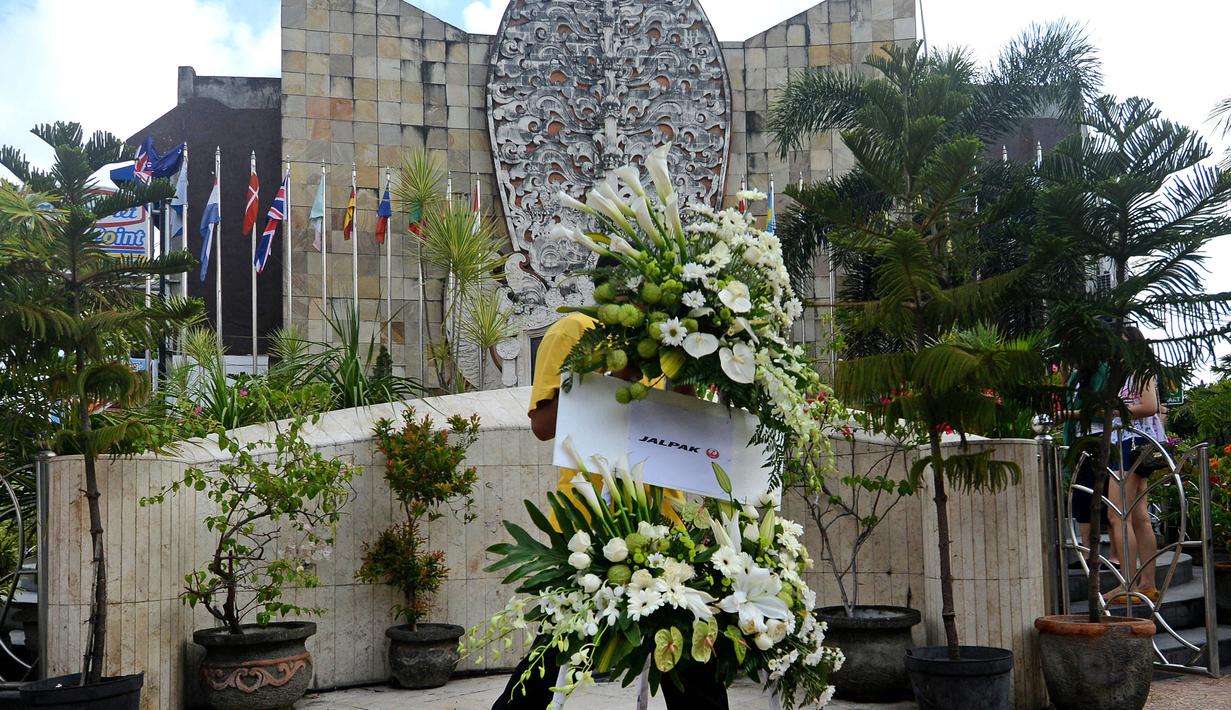 Seorang pria tampak membawa karangan bunga untuk memeperingati 13 tahun meledaknya bom bali 1 di depan monumen tragedi kemanusiaan,  Bali, Senin (12/10/2015). Hari ini tepat 13 tahun meledaknya bom bali 1. (AFP PHOTO/SONNY Tumbelaka)