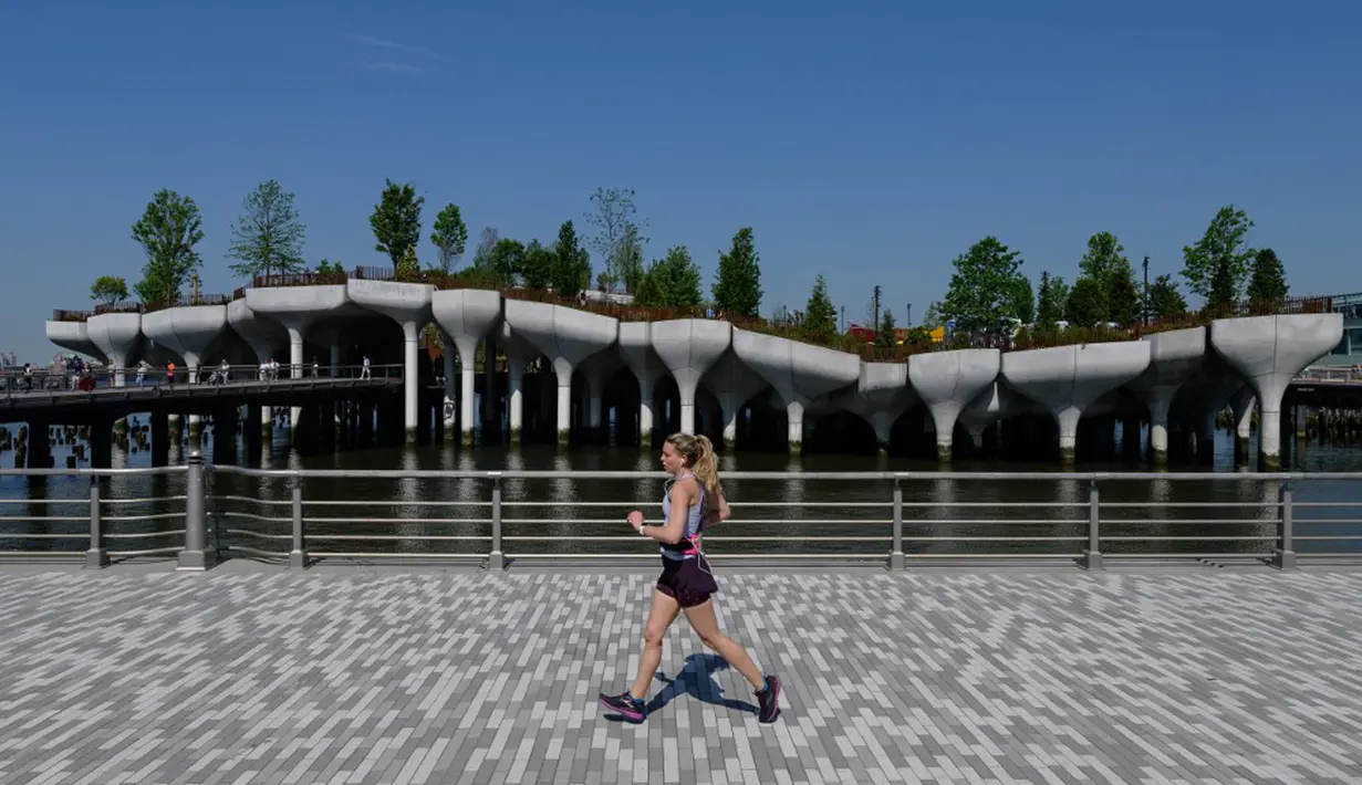 Seorang pelari berlari melewati 'Pulau Kecil', taman umum baru dan gratis di Hudson River Park, New York City, Amerika Serikat, 21 Mei 2021. Taman yang diresmikan pada 21 Mei 2021 tersebut menghabiskan dana sebesar USD USD 260 juta. (Angela Weiss/AFP)