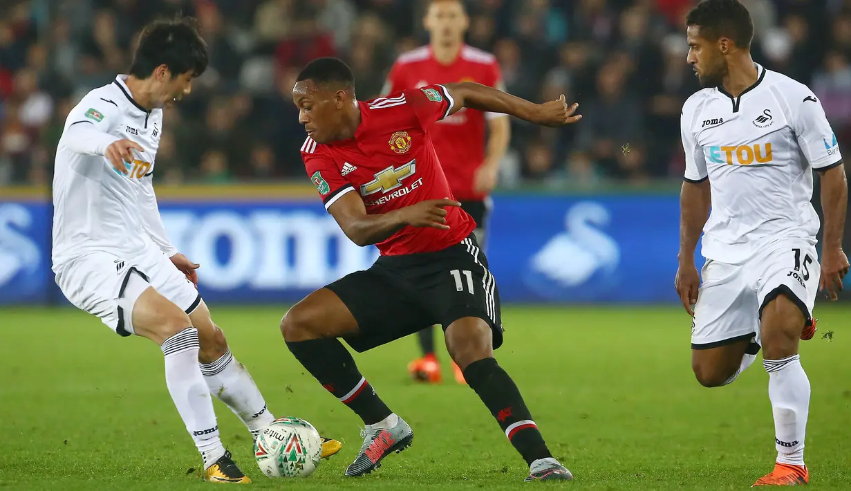 Striker Manchester United, Anthony Martial, berusaha melewati pemain Swansea City pada laga Piala Liga Inggris di Stadion Liberty, Swansea, Selasa (24/10/2017). Manchester United menang 2-0 atas Swansea City. (AFP/Geoff Caddick)