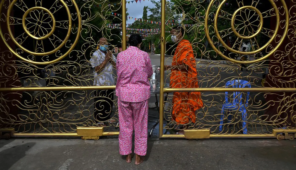 Warga antre untuk memberikan makanan dan sedekah kepada biksu Buddha saat Festival Pchum Ben (Festival Kematian) di luar pagoda di Phnom Penh, Kamboja, 24 September 2021. Pihak berwenang menghentikan perayaan Festival Kematian karena pandemi COVID-19. (TANG CHHIN Sothy/AFP)