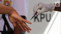 Warga diteteskan tinta di kelingking usai pemungutan suara pada Pilkada Tangerang Selatan di TPS 49 Cendana Residence, Pamulang, Rabu (9/12/2020). TPS 49 pada Pilkada Serentak 2020 mengusung tema Rindu Sekolah Lagi (Kisah-Kasih di Sekolah). (Liputan6.com/Fery Pradolo)