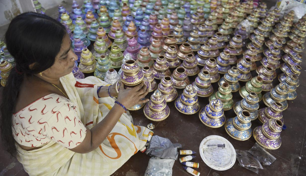 Perajin menunjukkan pot minyak tembikar atau diyas yang disimpan untuk dikeringkan menjelang Diwali, festival lampu Hindu, di luar bengkel di Hyderabad (4/11/2020). Diwali dirayakan selama lima hari berturut-turut.  (AFP Photo/Noah Seelam)