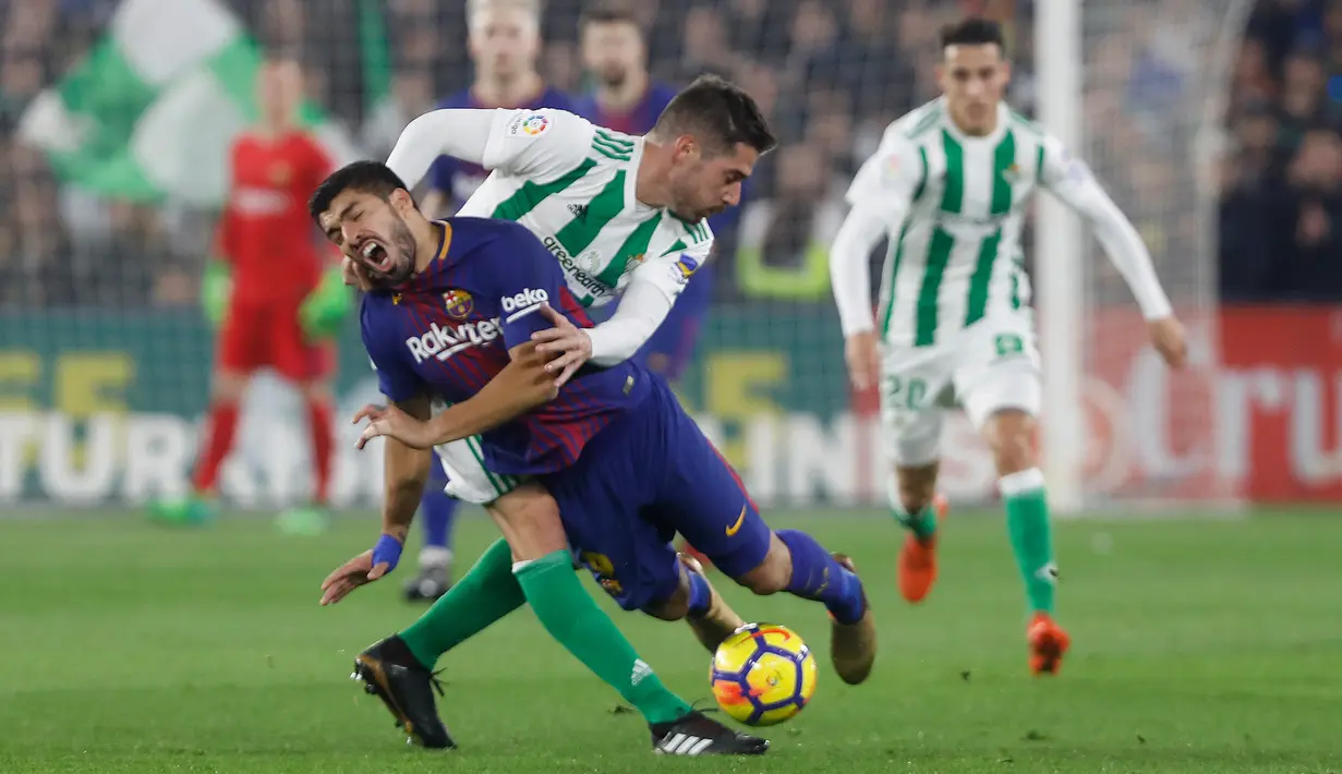 Pemain Barcelona Luis Suarez berebut bola dengan pemain Real Betis, Javi Garcia pada pertandingan lanjutan La Liga di Stadion Benito Villamarin, Minggu (21/1). Dua gol Suarez membawa Barcelona menang telak 5-0 atas Real Betis. (AP/Miguel Morenatti)