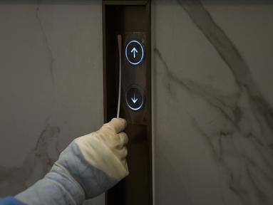 Pekerja medis mengumpulkan sampel dari tombol lift untuk pengujian COVID-19 di pusat media utama di Olimpiade Musim Dingin Beijing 2022, 11 Februari 2022. Tak hanya manusia, penyelenggara Olimpiade Beijing juga melakukan tes pada gagang pintu, tombol lift, sofa dan mesin ATM. (AP Photo/Jae C.Hong)