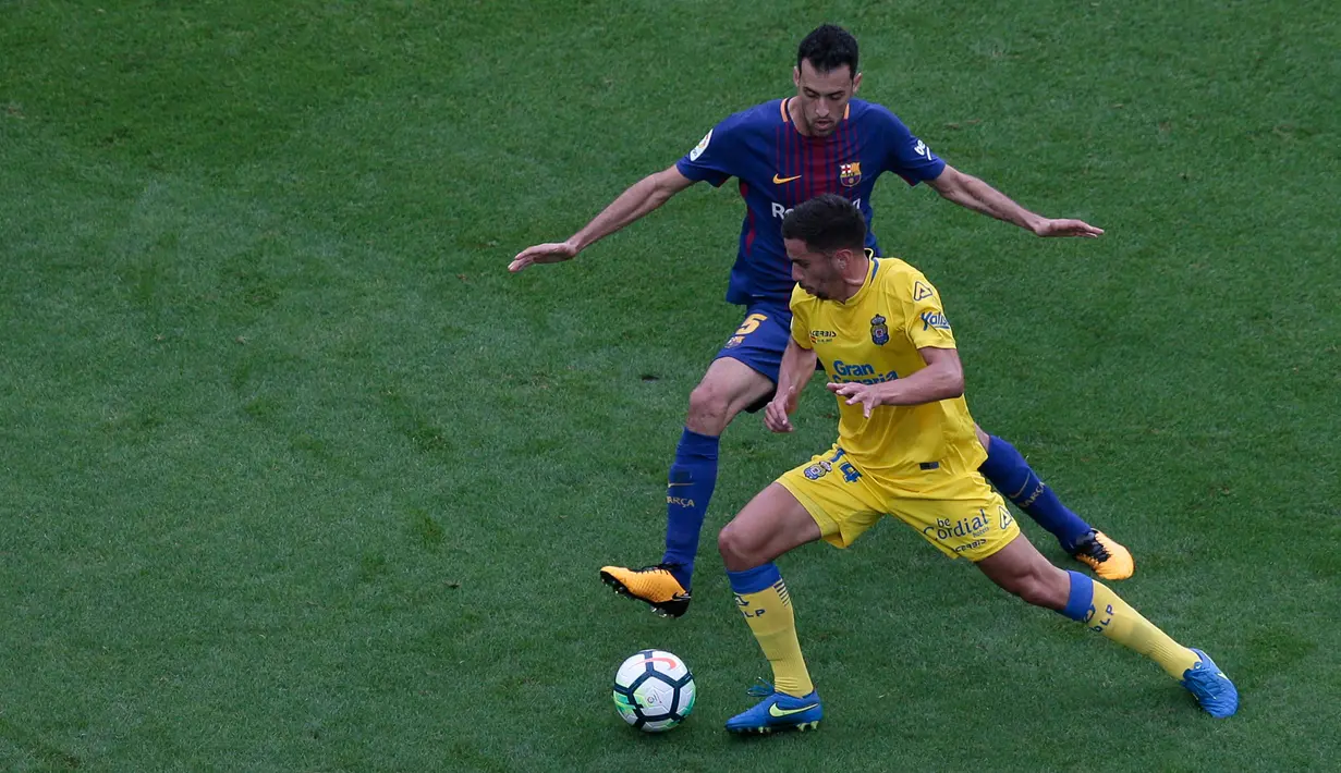 Pemain Barcelona, Sergio Busquets berebut bola dengan pemain Las Palmas, Hernan dalam pertandingan Liga Spanyol di Camp Nou, Senin (2/10) dini hari. Satu gol Busquets mewarnai kemenangan Barcelona3-0. (AP/Manu Fernandez)