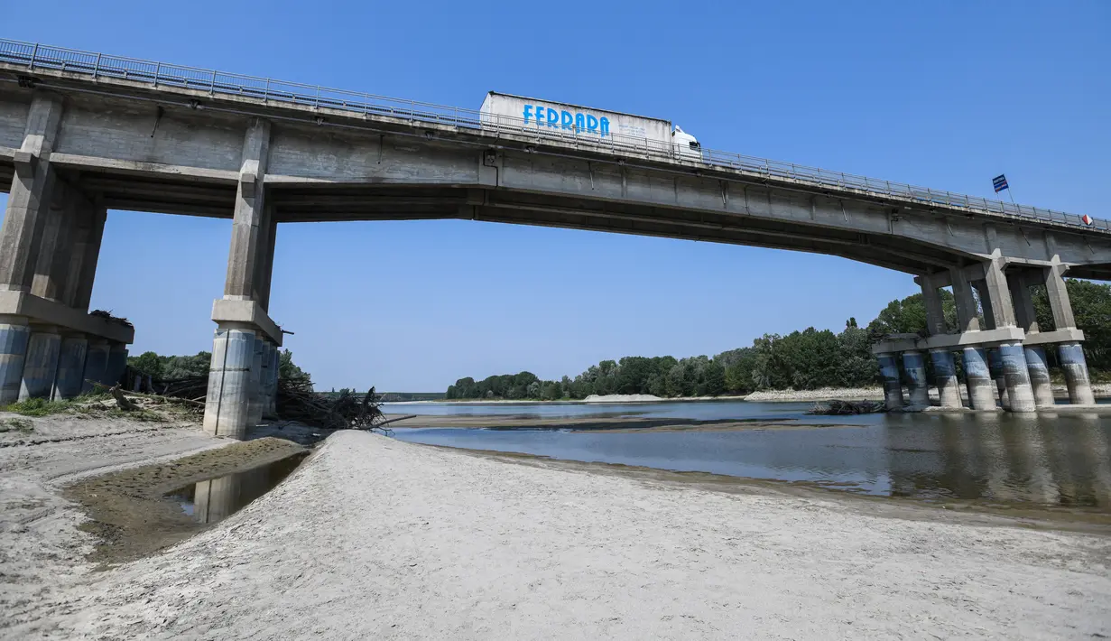 Kendaraan melintasi jembatan di atas dasar sungai Po yang mengering di Boretto, timur laut Parma, pada Rabu (15/6/2022). Menurut pengamat sungai, kekeringan yang mempengaruhi sungai terbesar di Italia, Po adalah yang terburuk dalam 70 tahun terakhir. (Piero CRUCIATTI / AFP)