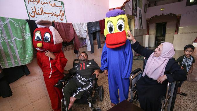 Nihad Jarboa (37) dan istrinya Zeinab (35), warga Palestina yang hidup dengan cacat fisik sejak masa kanak-kanak, duduk di kursi roda ketika klien mencoba kostum kartun yang mereka buat, di rumah mereka di kamp pengungsi Rafah di Gaza selatan Telanjangi, pada 19 Juli 2020. (AFP Photo/Said Khatib)